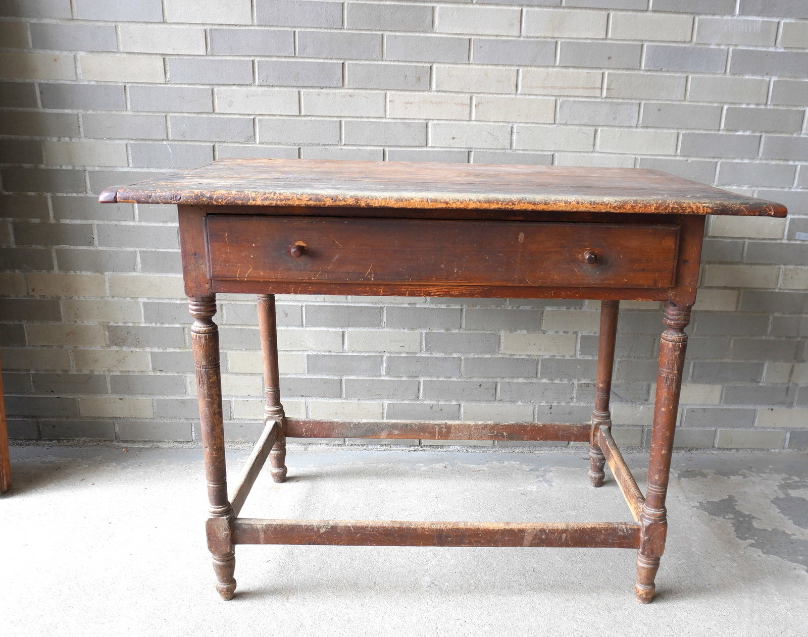 A 18th century tavern table with breadboard ends and center drawer, cross stretchers on turned legs.: A 18th century tavern table with breadboard ends and center drawer, cross stretchers on turned legs. All parts appear to be original. The top pinned into apron with wooden dowels. Overall fair conditi