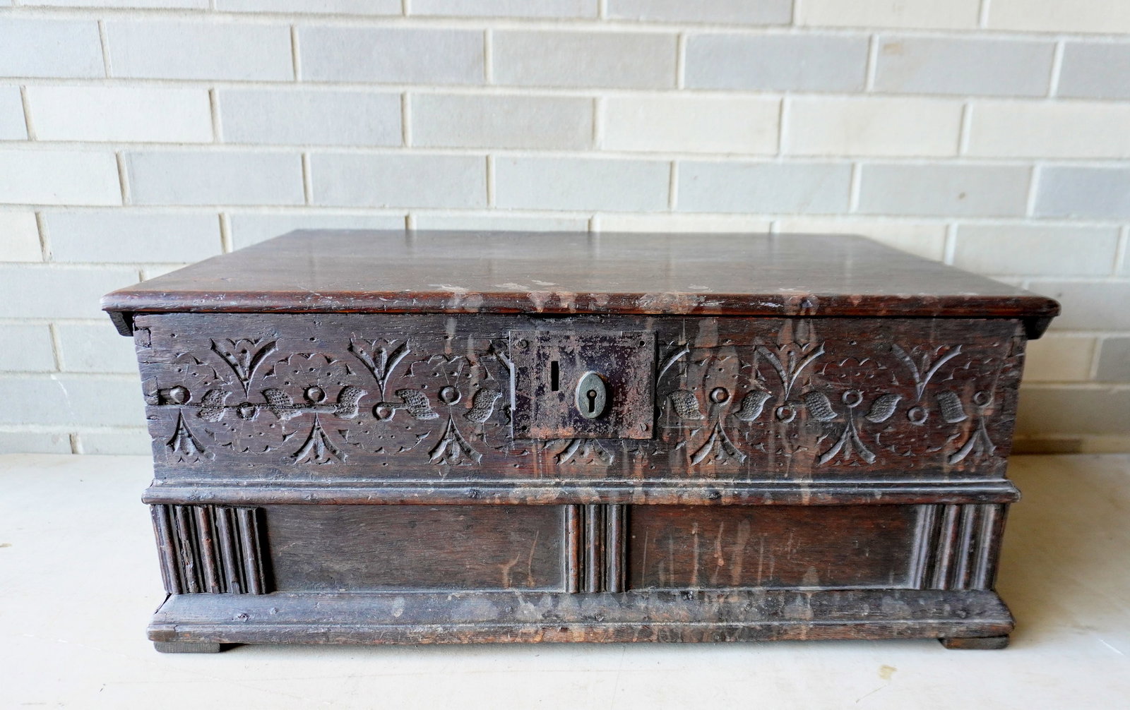 A large size oak Bible box or storage box, with molded edge to lid with repair, carved decorations: A large size oak Bible box or storage box, with molded edge to lid with repair, carved decorations over panels on front and sides, molded base, short rattail hinges, side cleats, iron lock appears to 