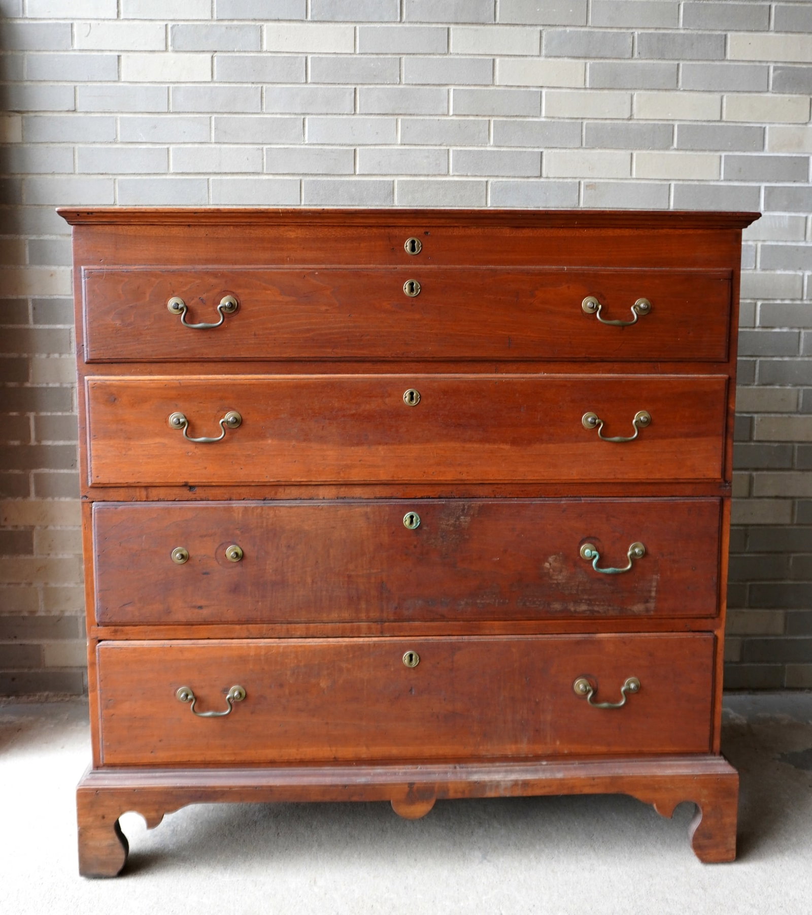 A New England 2 drawer blanket chest in butternut having 2 false drawers over 2 drawers on replaced: A refinished New England 2 drawer blanket chest in butternut having 2 false drawers over 2 drawers on an older replaced bracket base. Bale pulls appear to be original (one missing handle) and the orig