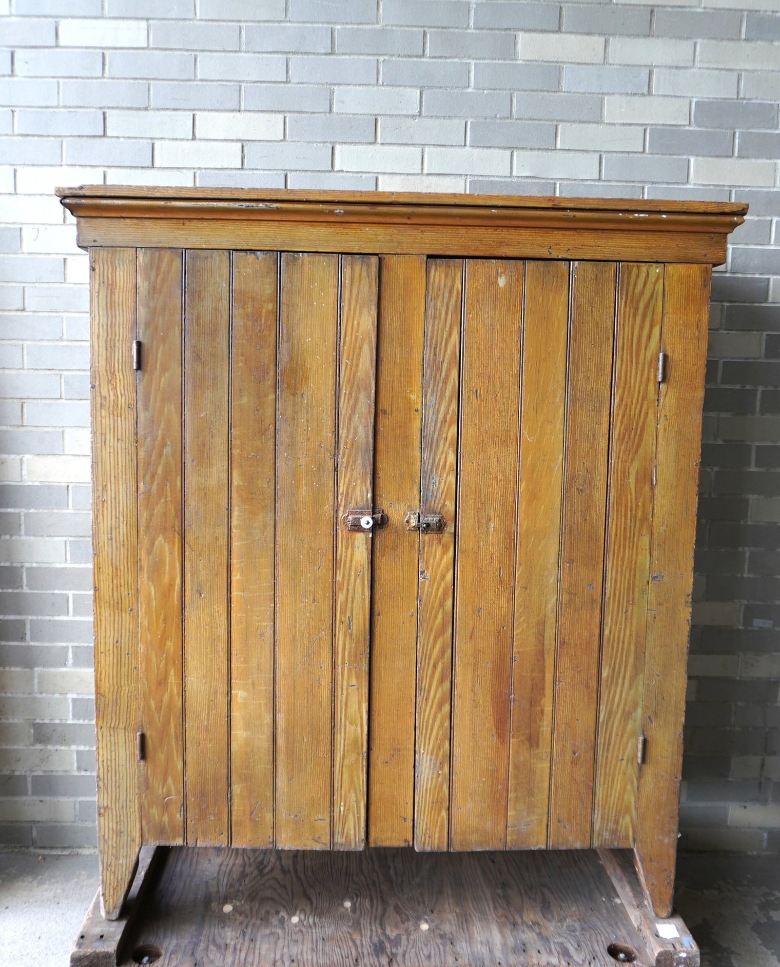 A grain painted 2 door cupboard in mustard color paint over original blue/gray, probably: A grain painted 2 door cupboard in mustard color paint over original blue/gray, probably Pennsylvania circa 1870-80. The 2 front doors in wainscot, side panels 1 piece. Missing one of the porcelain pu
