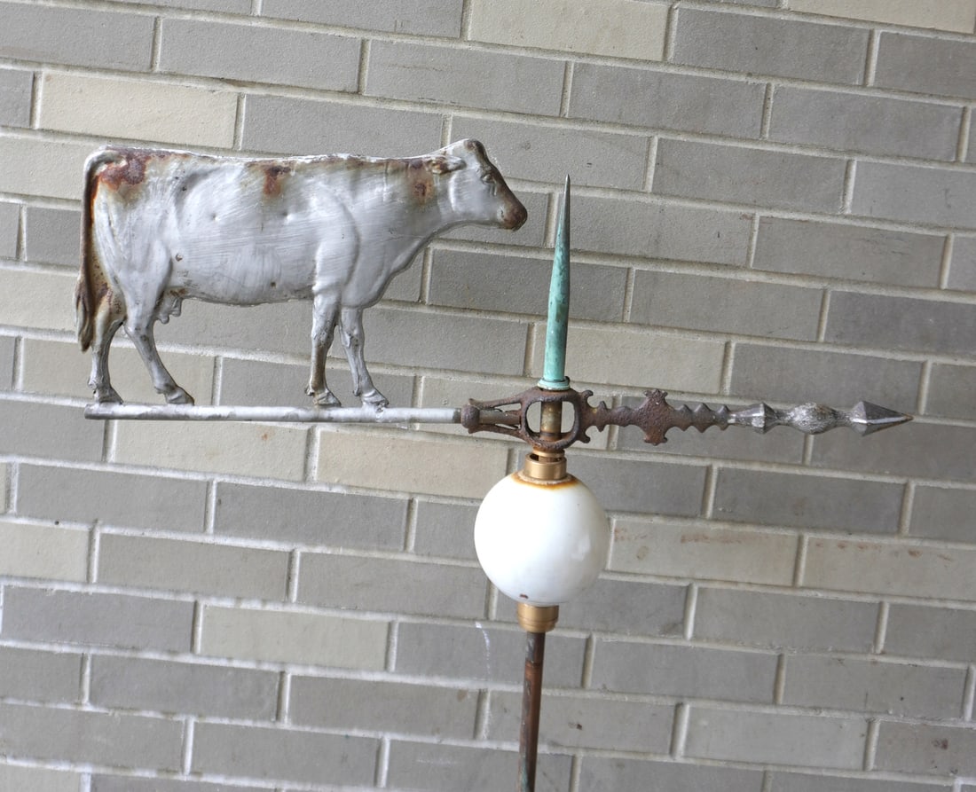 A lightening rod with painted tin cow mounted on arrow directional over milk glass ball. No roof: A lightening rod with painted tin cow mounted on arrow directional over milk glass ball. No roof mounting brackets, but the vane itself is all original in old gray paint, late 19th century. Provenance