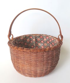 A round Taghkanic swing handle basket with pushed up bottom and crisscrossed rim, 19th century.