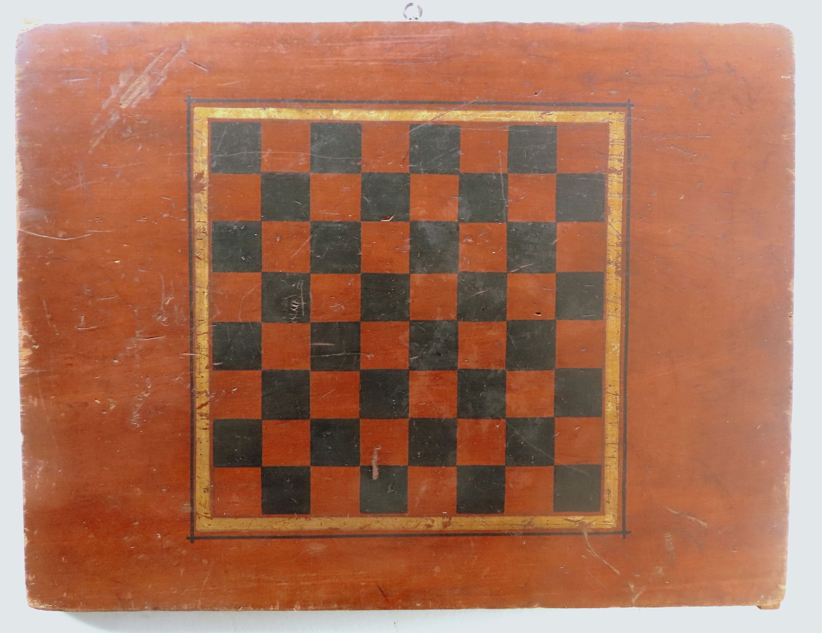 An American hand painted gameboard with black and cider-brown squares and green, gold and black: An American hand painted gameboard with black and cider-brown squares and green, gold and black border, late 19th century. One board construction with an inset spline on each end to assist in shrinkag