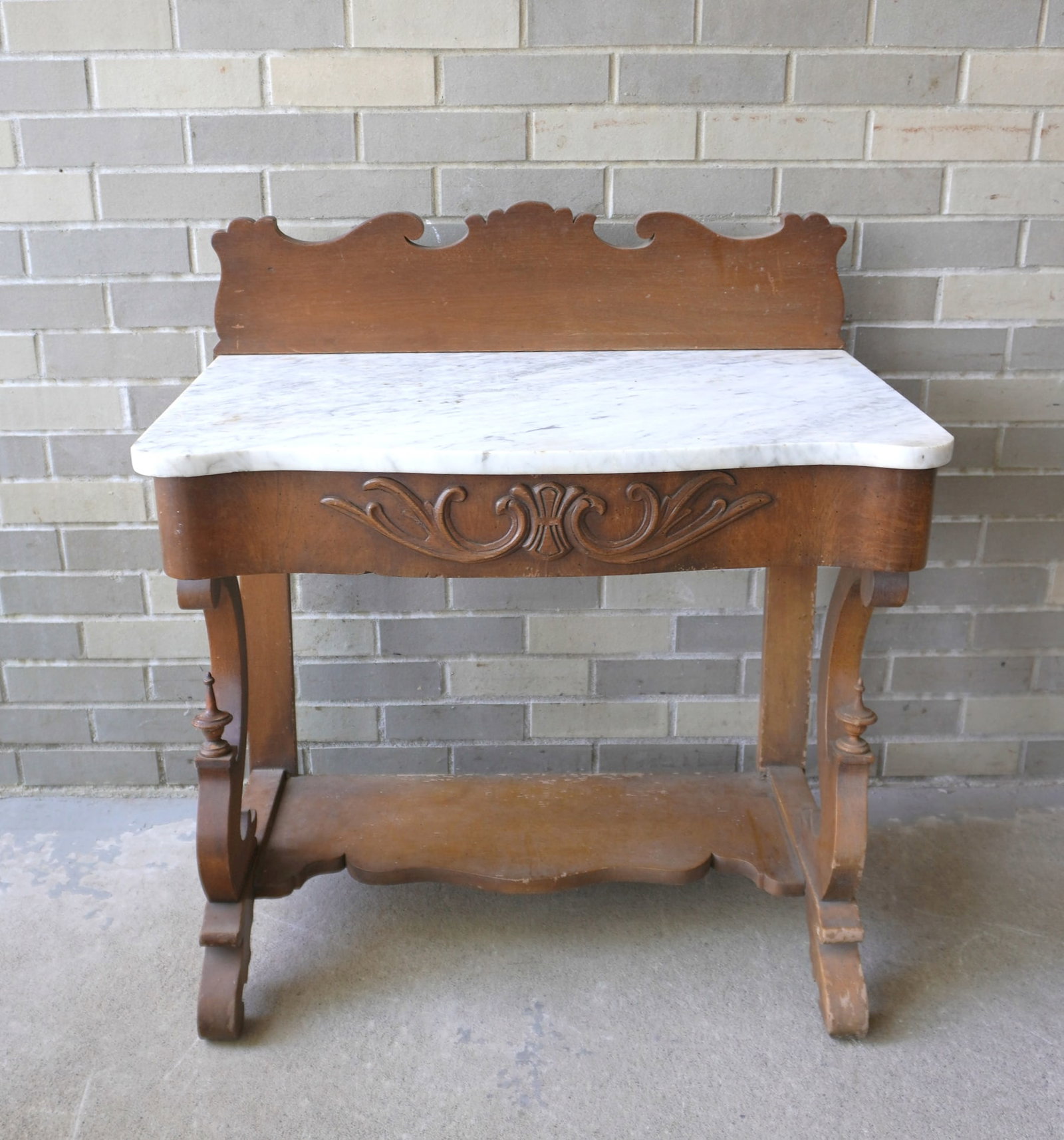 Victorian marble top table with serpentine front, shaped backsplash, over decorated center drawer: Victorian marble top table with serpentine front, shaped backsplash, over decorated center drawer and carved legs with lower shelf. Use wear. Repairs to the top of both rear legs, otherwise good condi