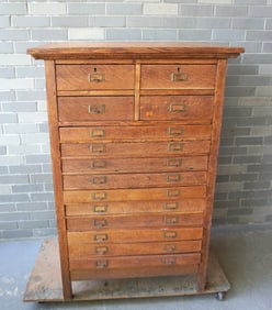An oak multi-drawer file cabinet, 4 large drawers over 10 shallow drawers. Likely for drawings,