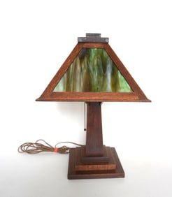 An Arts & Crafts oak slag glass table lamp with 4 green slag glass panels, and having a stepped