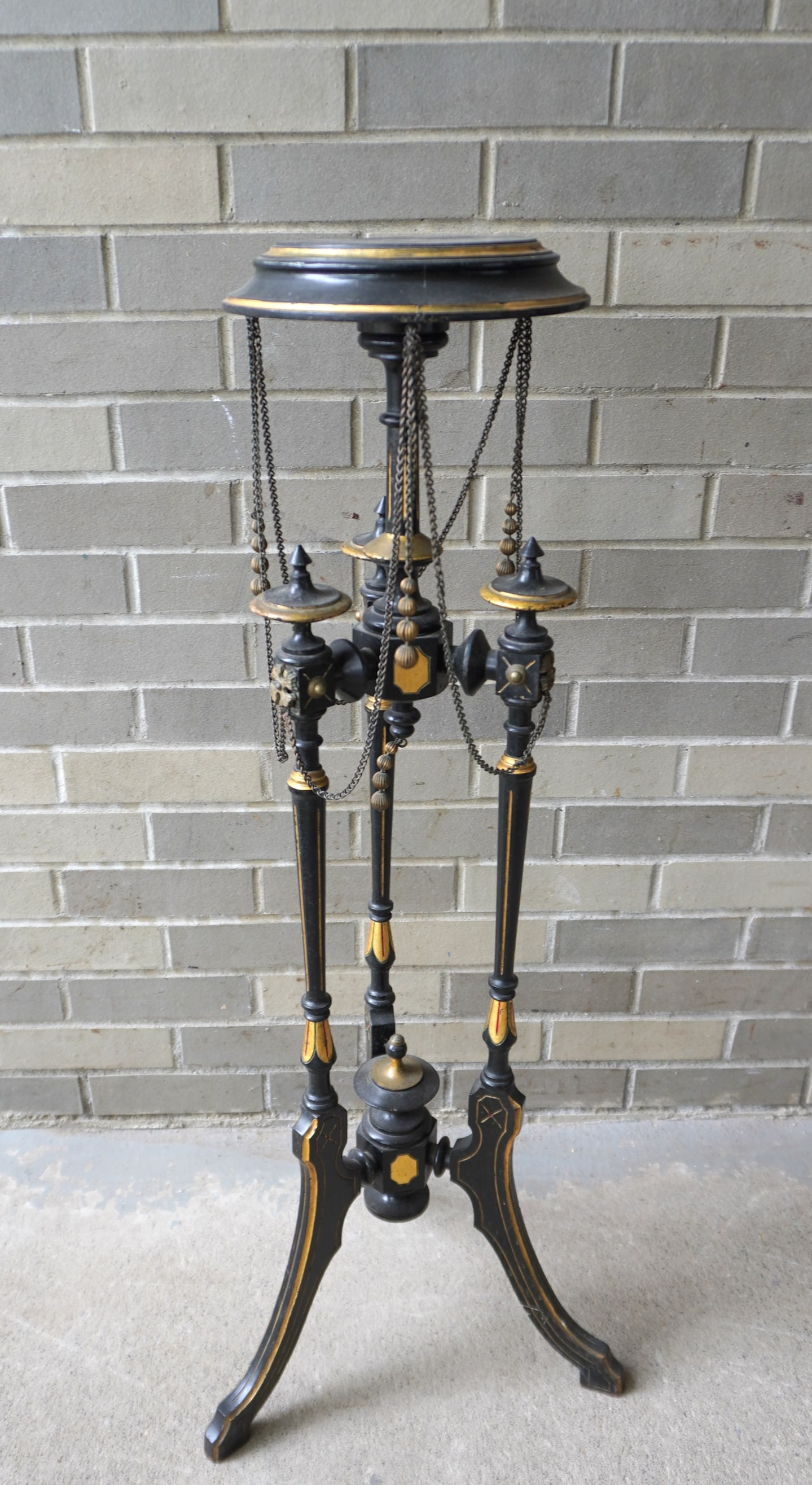 An ornate ebonized Renaissance Revival plant stand with rosettes and hanging brass chains and: An ornate ebonized Renaissance Revival plant stand with rosettes and hanging brass chains and tassels, circa 1870-80. Minor use wear, appears complete and in good overall condition. Measures 16" diame