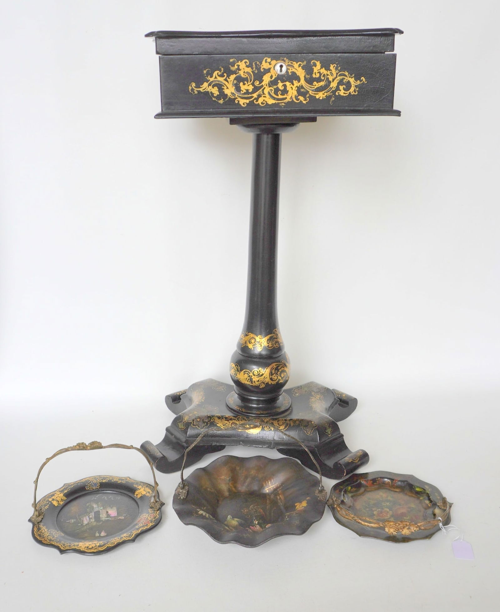 A grouping of 19th century paper mache articles including: A black lacquered sewing stand decorated: A grouping of 19th century paper mache articles including: A black lacquered sewing stand decorated with gilded scrolls and flowers and having a top decorated with flowers with mother of pearl inlays