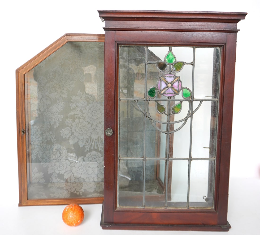 Two wall hanging display cabinets. The first with leaded and stained glass door and side panels with: Two wall hanging display cabinets. The first with leaded and stained glass door and side panels with floral decorations, no backing, 2 glass shelves - missing small piece of molding on side panel, but