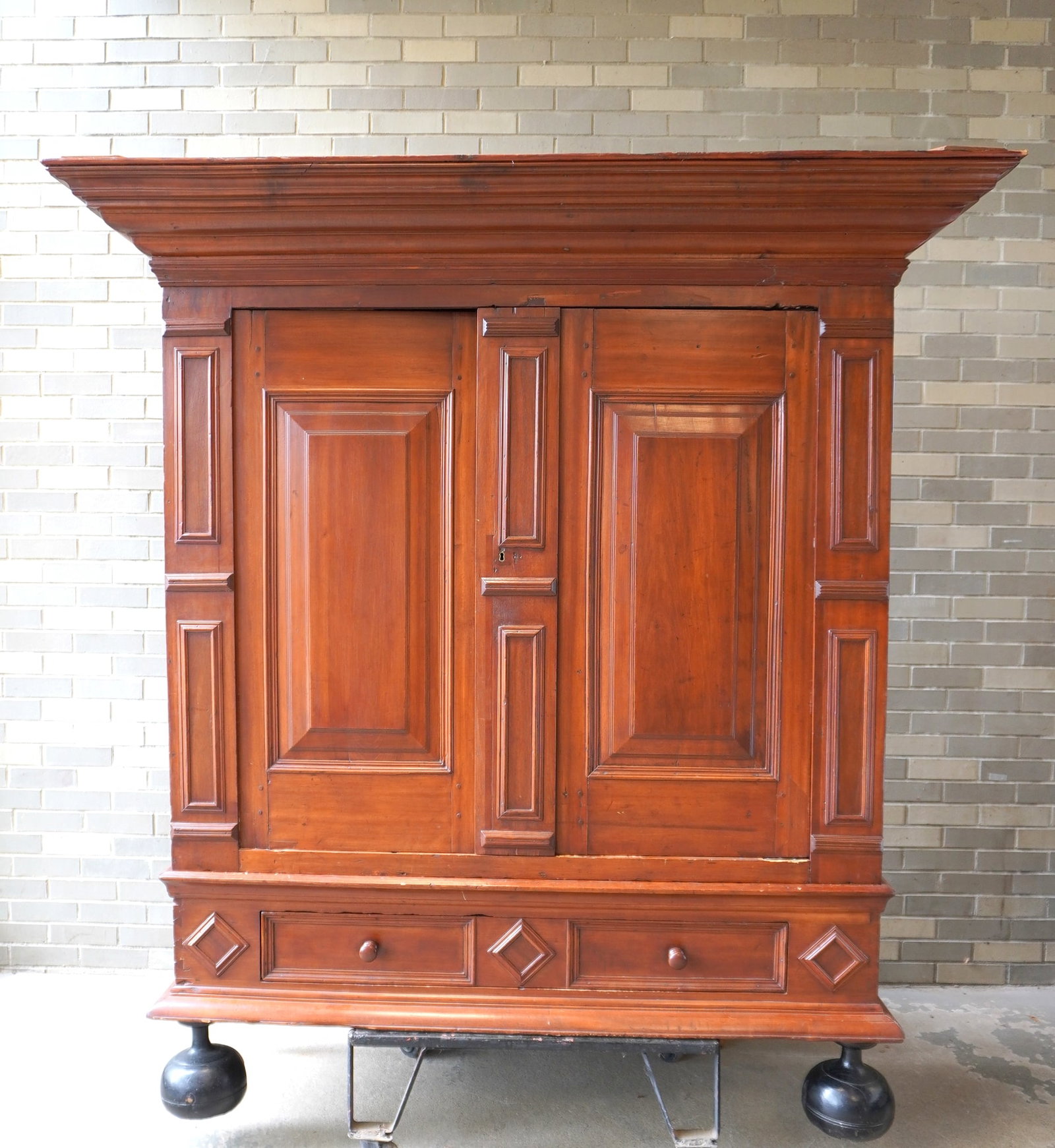 A Hudson Valley Kas attributed to the Elting-Beekman shop, Kingston NY, circa 1700-30. The kas with: A Hudson Valley Kas attributed to the Elting-Beekman shop, Kingston NY, circa 1700-30. The kas with a large stepped cornice over 2 raised paneled doors, interior shelves, long lower drawer decorated w