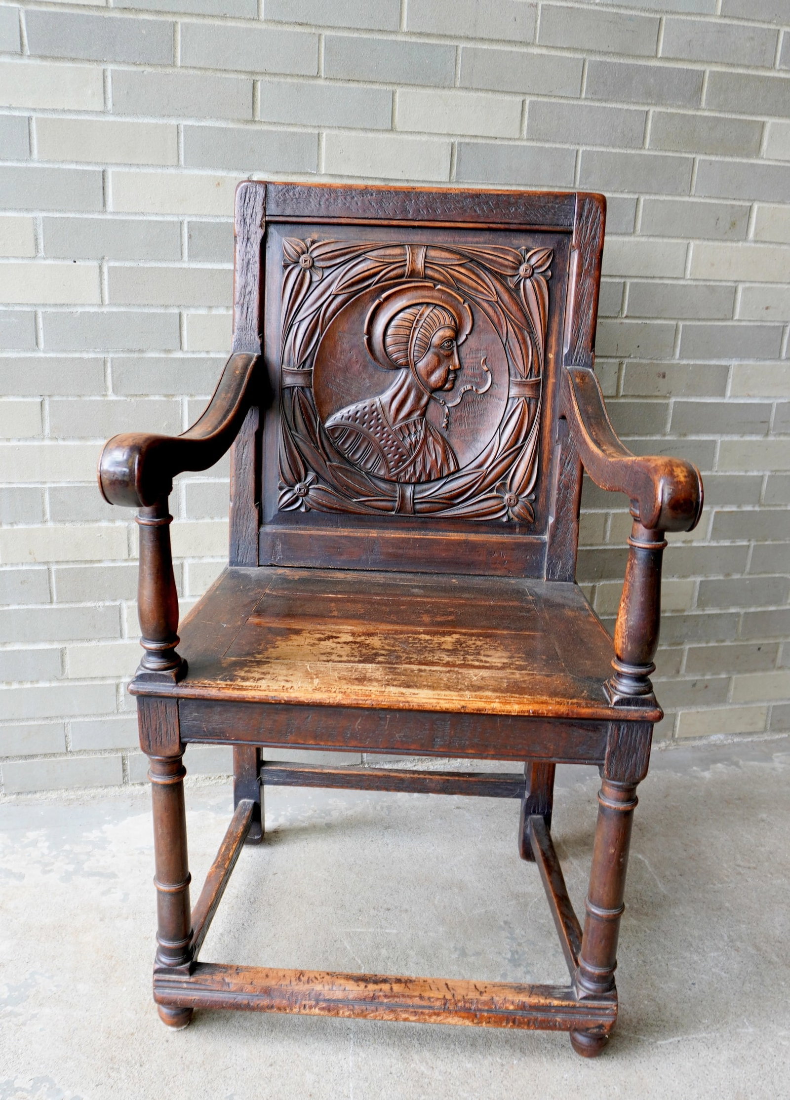 A Jacobean style religious chair with a carved Saint on the back and having rolled arms and turned: A Jacobean style religious chair with a carved Saint on the back and having rolled arms and turned feet with cross-stretchers, 19th century. Very good condition with expected use wear and in original 