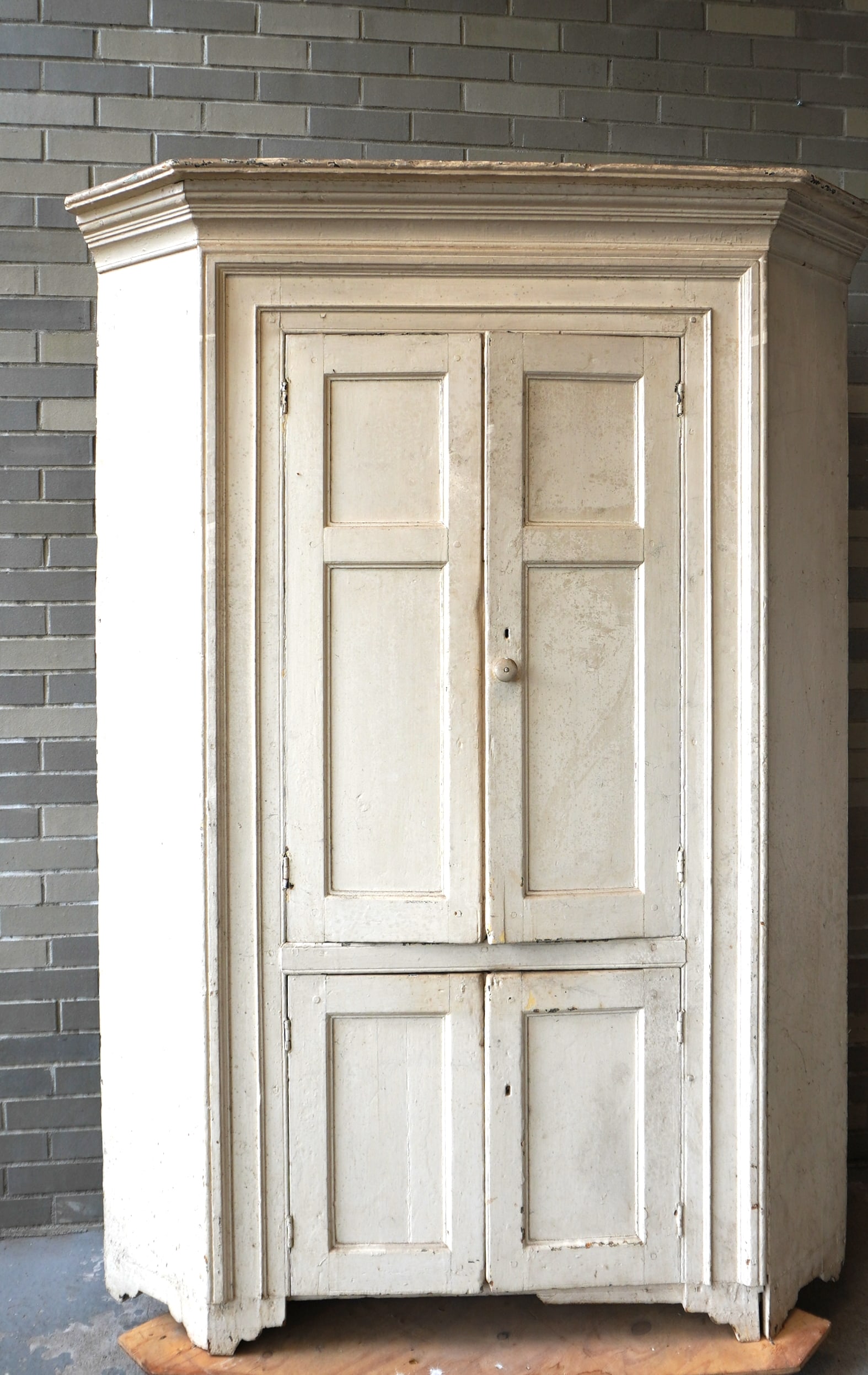 A Hudson Valley barrel back corner cupboard having its original stepped cornice, 2 long paneled: A Hudson Valley barrel back corner cupboard having its original stepped cornice, 2 long paneled doors over 2 short paneled doors, the top section with lolly-pop shelves, mounted on cutout base, circa 