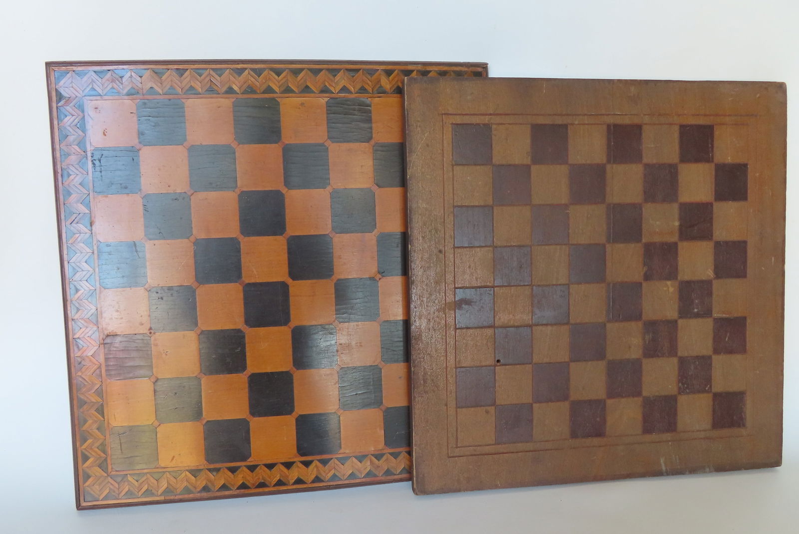 Two vintage American gameboards. The first constructed with inlays including what appears to be: Two vintage American gameboards. The first constructed with inlays including what appears to be ebony and satinwood squares and having inlaid zig-zag border with stepped molding applied to perimeter -