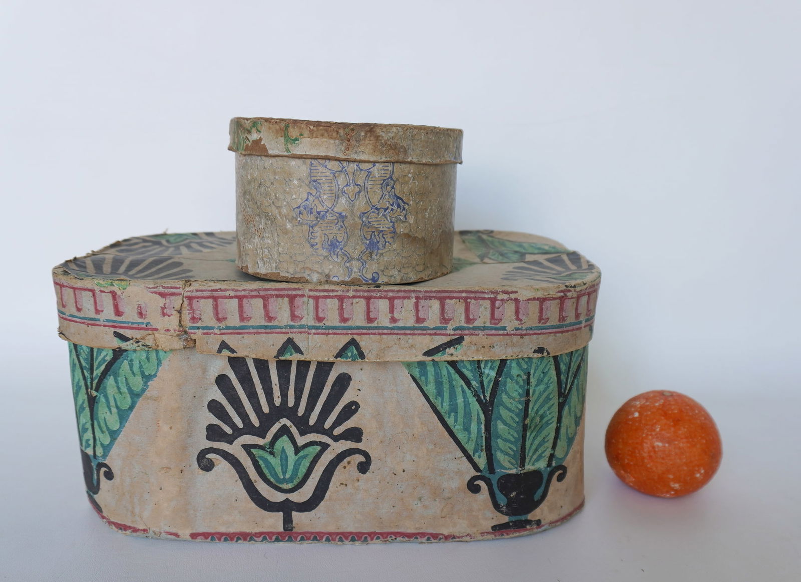 Two early wallpapered bandboxes, including a rectangular probably for hats and a smaller round: Two early wallpapered bandboxes, including a rectangular probably for hats and a smaller round example for holding collars, both lined with vintage newspapers, circa 1830. Both with expected use wear