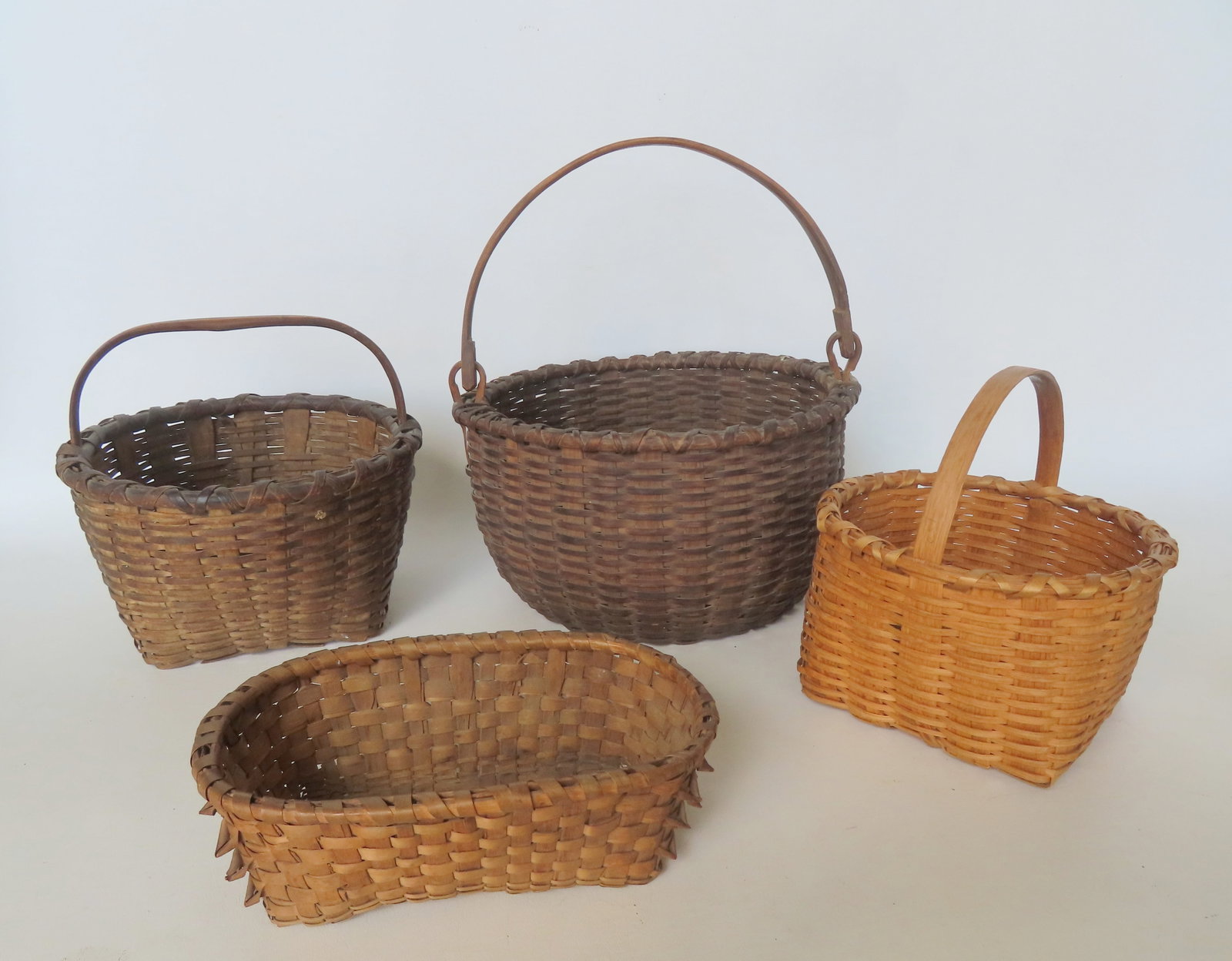 Grouping of 5 good country baskets including: Taghkanic swing handle with crisscrossed rim and: Grouping of 5 good country baskets including: Taghkanic swing handle with crisscrossed rim and pushed up bottom - several small splint break in base, otherwise excellent patination and in good conditi