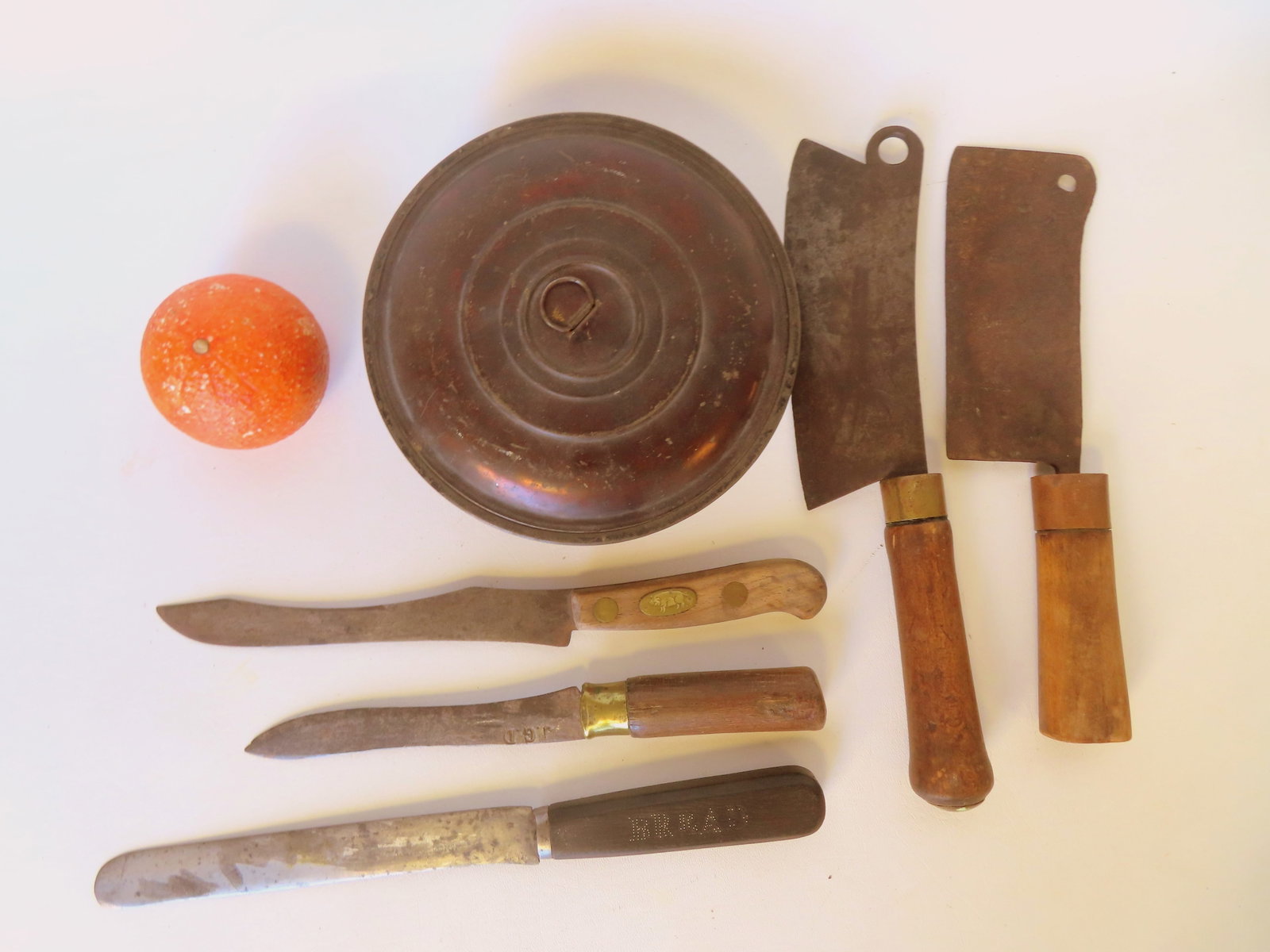 Grouping of butchering bread cutting tools and a toleware spice box. The tools include a knife with: Grouping of butchering bread cutting tools and a toleware spice box. The tools include a knife with a brass inlay in handle in the form of a pig, and a chopping tool with blade engraved with date 1867