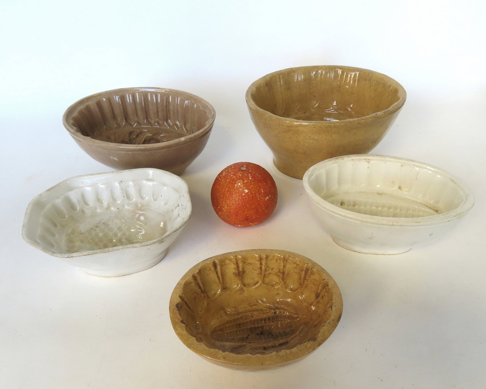 Grouping of 5 jello or pudding molds, 2 in yellowware and 3 in ironstone, all 19th century and in: Grouping of 5 jello or pudding molds, 2 in yellowware and 3 in ironstone, all 19th century and in used but good condition. The largest, the yellowware mold with grape pattern, measures 7 3/4"L x 4 1/4