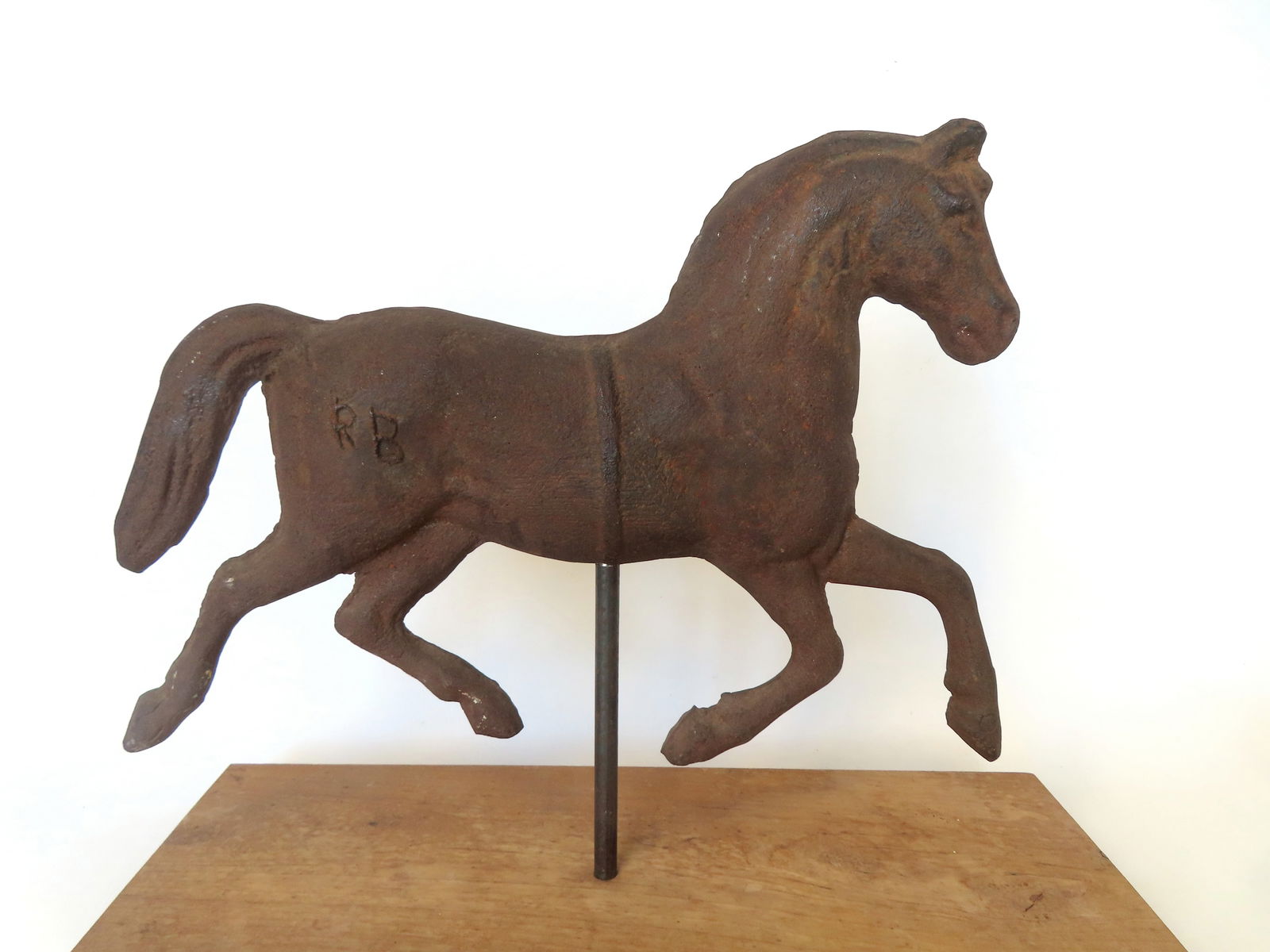 A solid cast iron figure of a trotting horse marked "RB" on hindquarters, mid 19th century or: A solid cast iron figure of a trotting horse marked "RB" on hindquarters, mid 19th century or earlier. See marks on mane side of horse indicating it was attached to a larger object. Currently mounted