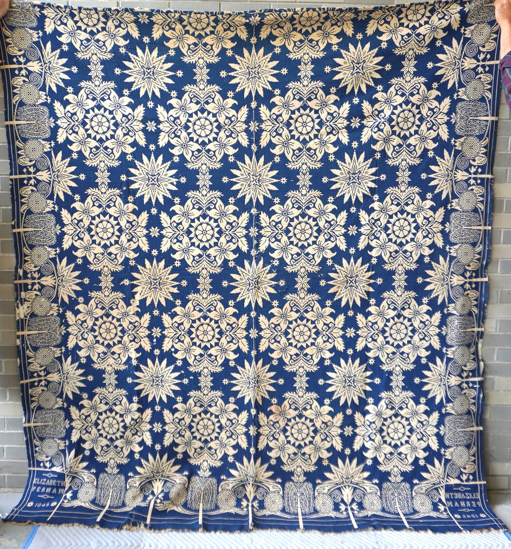 A Jacquard blue and white coverlet signed in corners Elizabeth Perham 1845. The border decorated: A Jacquard blue and white coverlet signed in corners Elizabeth Perham 1845. The border decorated with stylized flowers and weeping willow trees. The central field decorated with flowers and stars. Los
