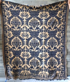 A Jacquard blue and white coverlet having a border decorated with a series of buildings and trees