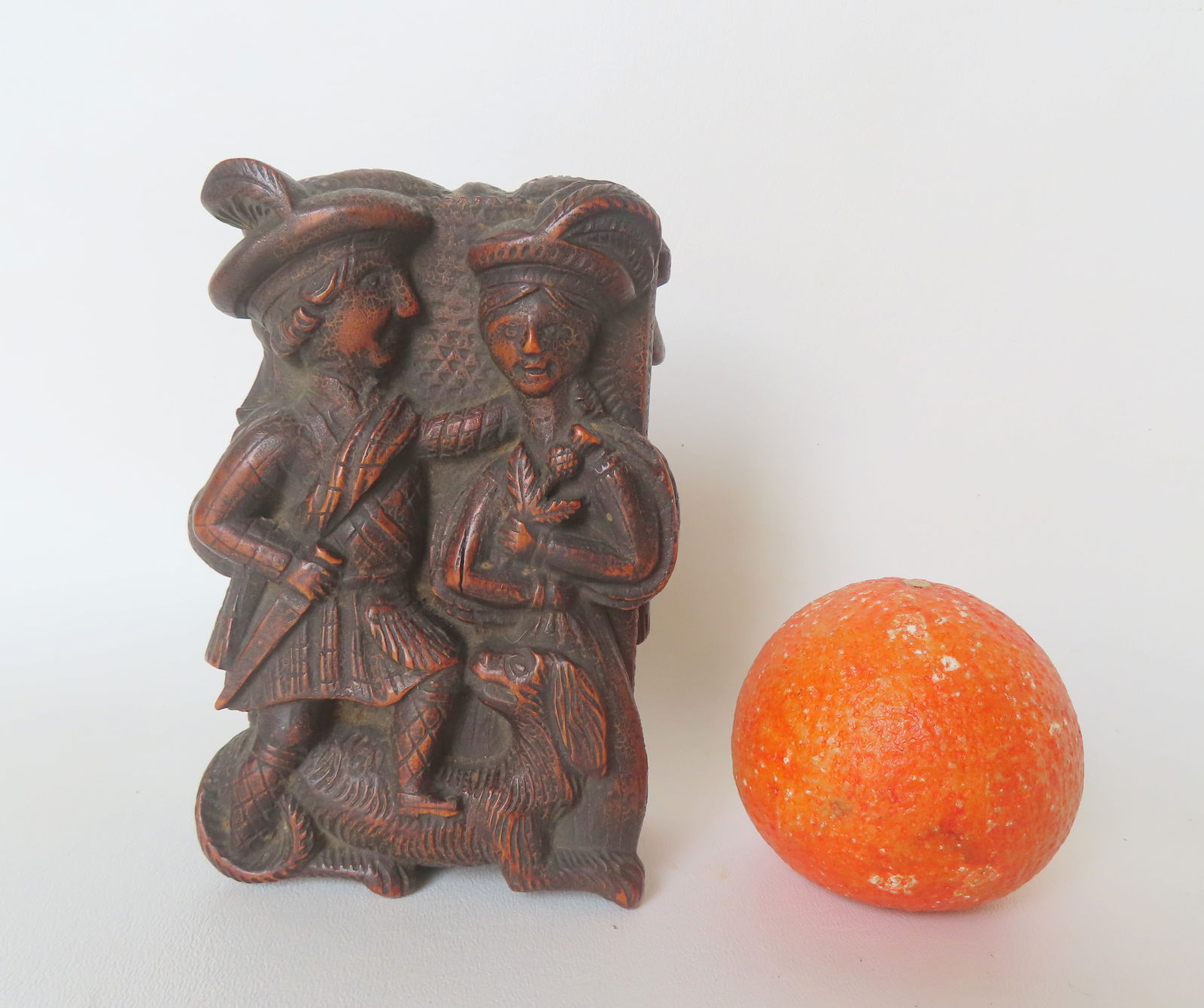 A Scottish snuff or tobacco box, high relief carving of figures and decorated on the hinged lid with: A Scottish snuff or tobacco box, high relief carving of figures and decorated on the hinged lid with a Scottish man and woman above reclining dog - the reverse side with carved figures of 2 men in a p