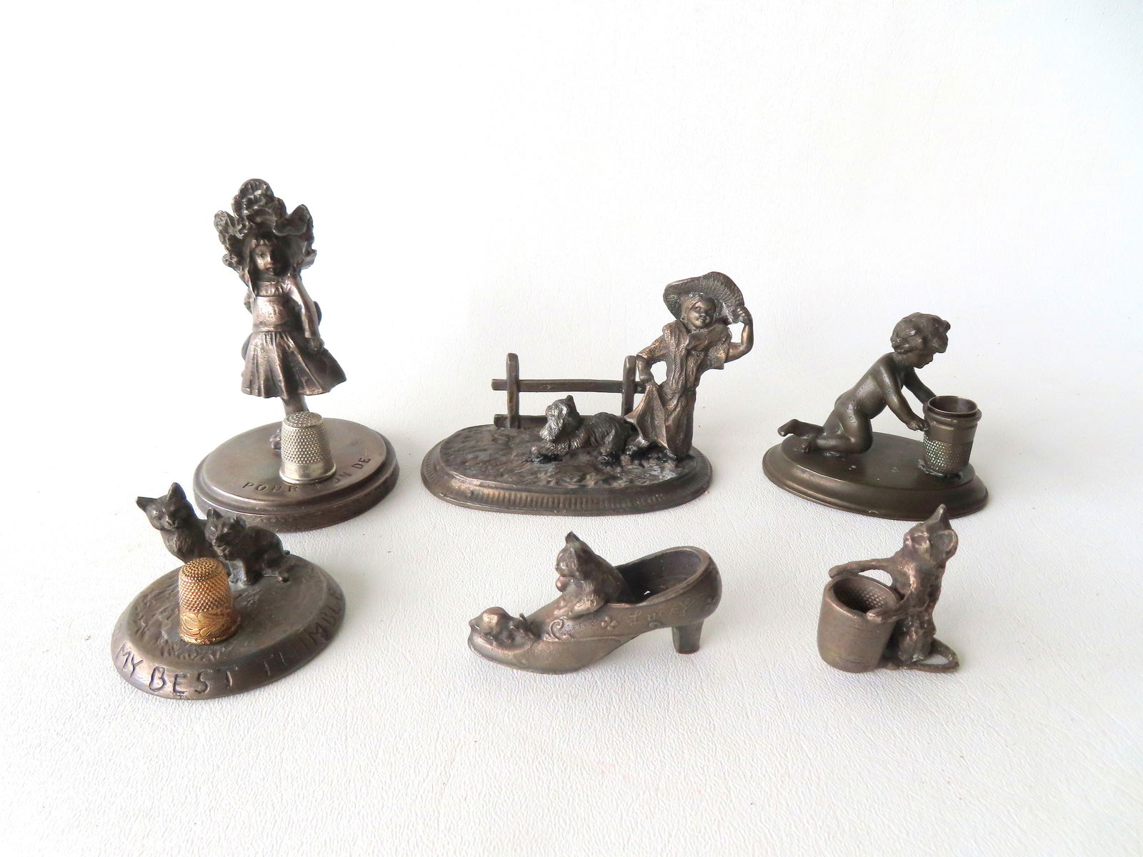 Grouping of 6 miniature figural sculptures, all likely 19th century, including 3 thimble holders:: Grouping of 6 miniature figural sculptures, all likely 19th century, including 3 thimble holders: Zinc thimble holder of young girl wearing bonnet, engraved on stand "Pour Mon De" (For My....) - 4 1/4