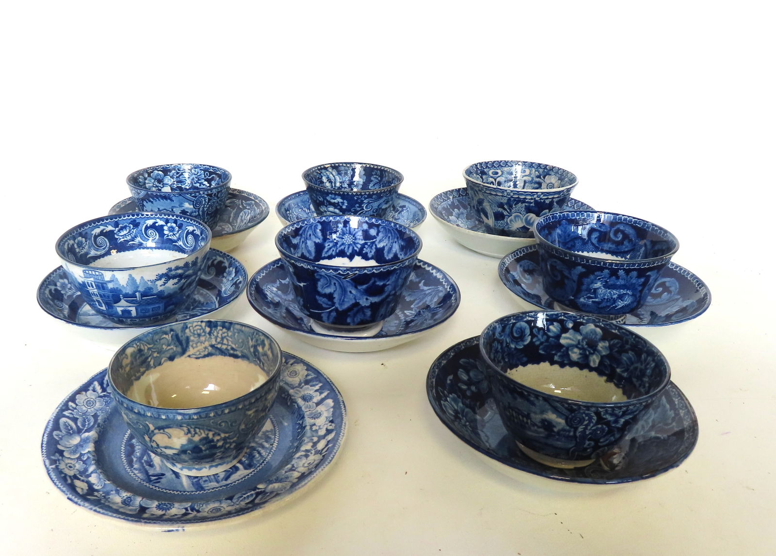 Grouping of 8 Staffordshire flow blue tea cups and matching saucers, various patterns. Two saucers: Grouping of 8 Staffordshire flow blue tea cups and matching saucers, various patterns. Two saucers and 1 tea cup with rim chip, on cup with stains on interior and hairline, else all in very good condi