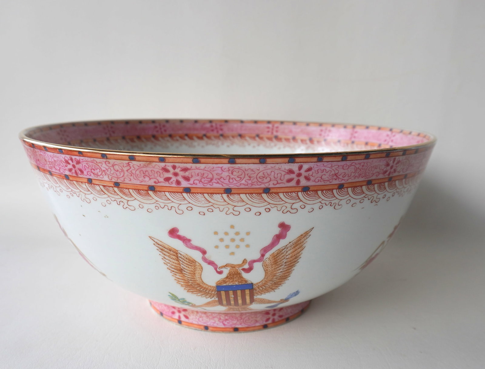 A Chinese export porcelain punch bowl decorated with flowers and spread wing American eagles wearing: A Chinese export porcelain punch bowl decorated with flowers and spread wing American eagles wearing American shields and having a pink luster border - unknown Chinese mark on footed base - very good 