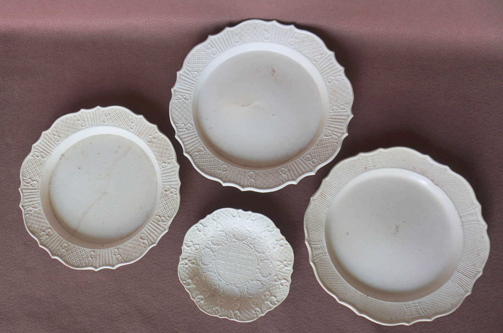 Three early salt glazed off-white chargers and one salt glazed off-white plate, all probably: Three early salt glazed off-white chargers and one salt glazed off-white plate, all probably Staffordshire circa 1760. The largest charger measures 15 1/8" diameter and has a tight hairline hardly not