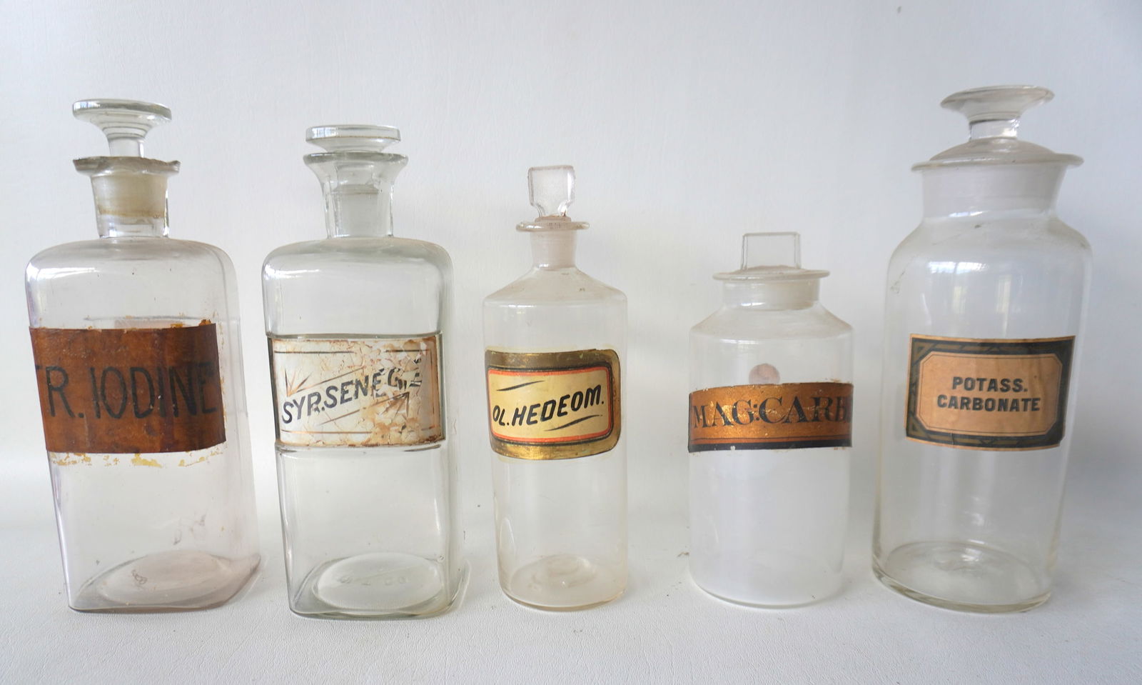 Grouping of 5 apothecary jars with original labels. The one marked Iodine has chips to the edge of: Grouping of 5 apothecary jars with original labels. The one marked Iodine has chips to the edge of rim and is the largest measuring 9 7/8"H, the others in very good condition including the 3 smaller b