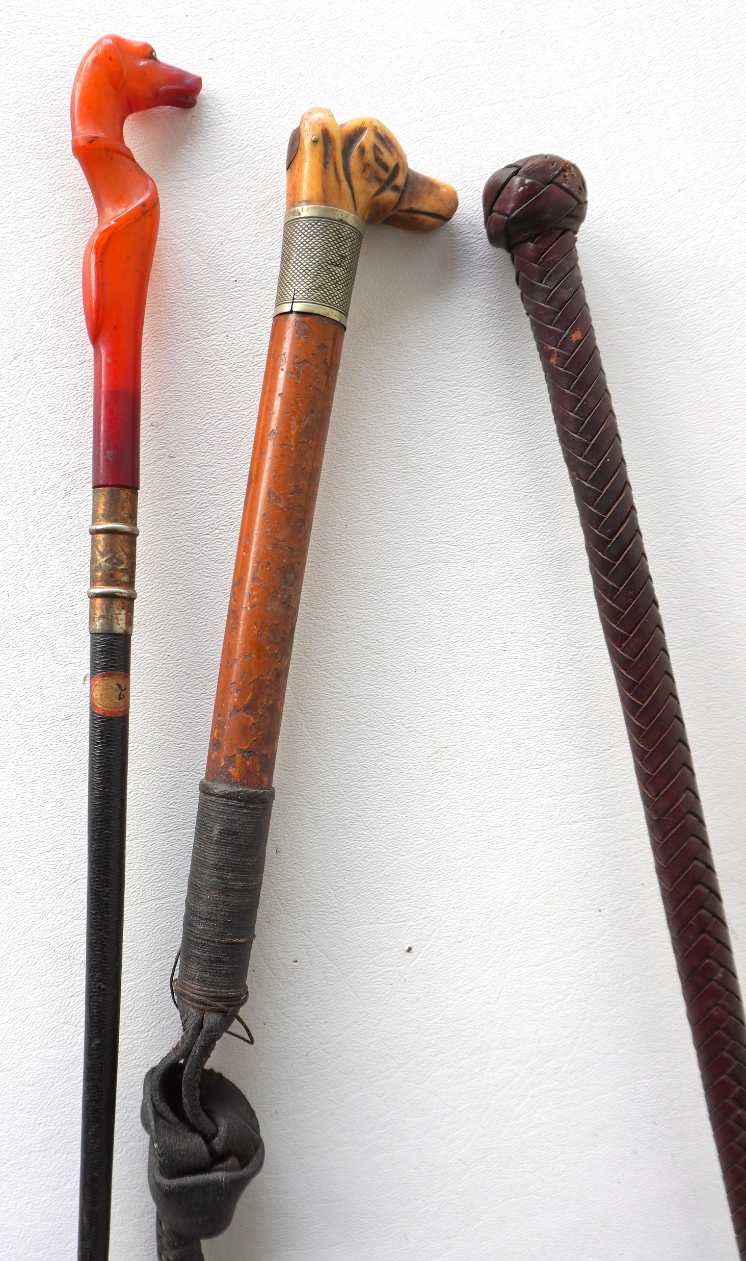 Three vintage riding crops including: The first with a carved bone head and silver collar - the: Three vintage riding crops including: The first with a carved bone head and silver collar - the woven leather whip with wear on the end, is broken from handle so it is in 2 pieces, else the handle in