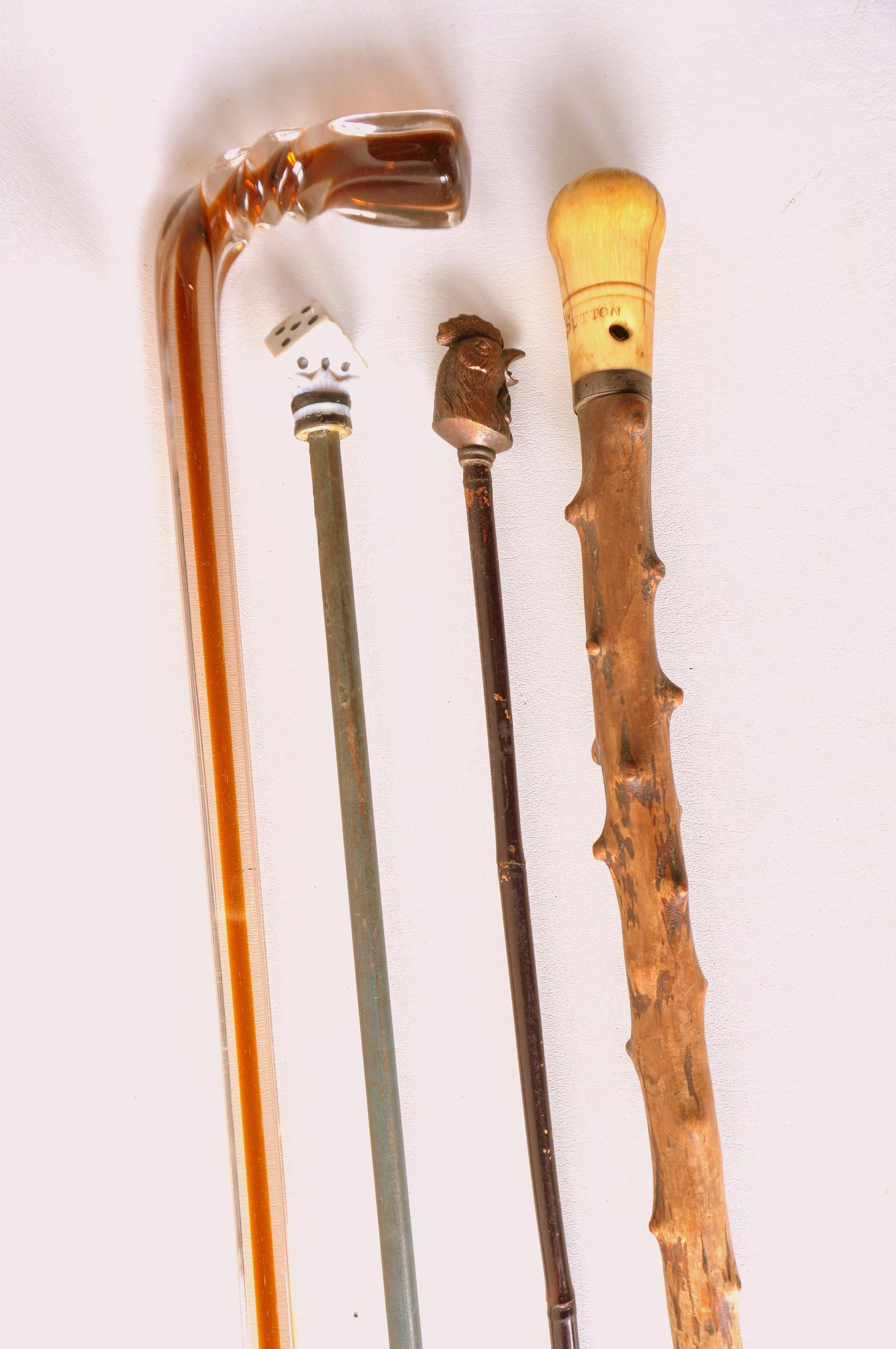 Four vintage walking sticks including: Bone handle, signed H. Sutton, early 19th century - good: Four vintage walking sticks including: Bone handle, signed H. Sutton, early 19th century - good condition - 35 3/4"L; porcelain handle in the form of a di - circa 1950; a Carnival cane with a gilded m