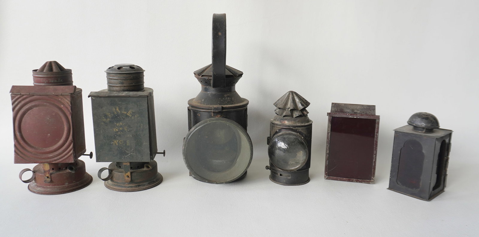 Grouping of 6 various lanterns including: The largest, with loop handle and beveled glass lens that: Grouping of 6 various lanterns including: The largest, with loop handle and beveled glass lens that opens to interior with brass reflector and tin lamp (the lamp missing removable burner) - good condi