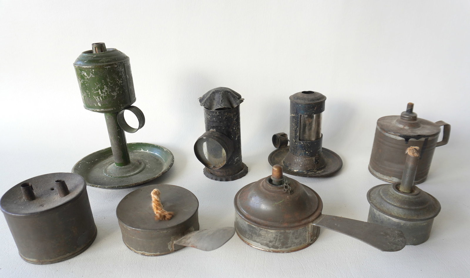 Grouping of 8 early tin lighting devices including: Small candle lantern with finger holder and: Grouping of 8 early tin lighting devices including: Small candle lantern with finger holder and crimped bottom with glass lens that opens from front - wear to paint otherwise good condition - 4 1/2"H;