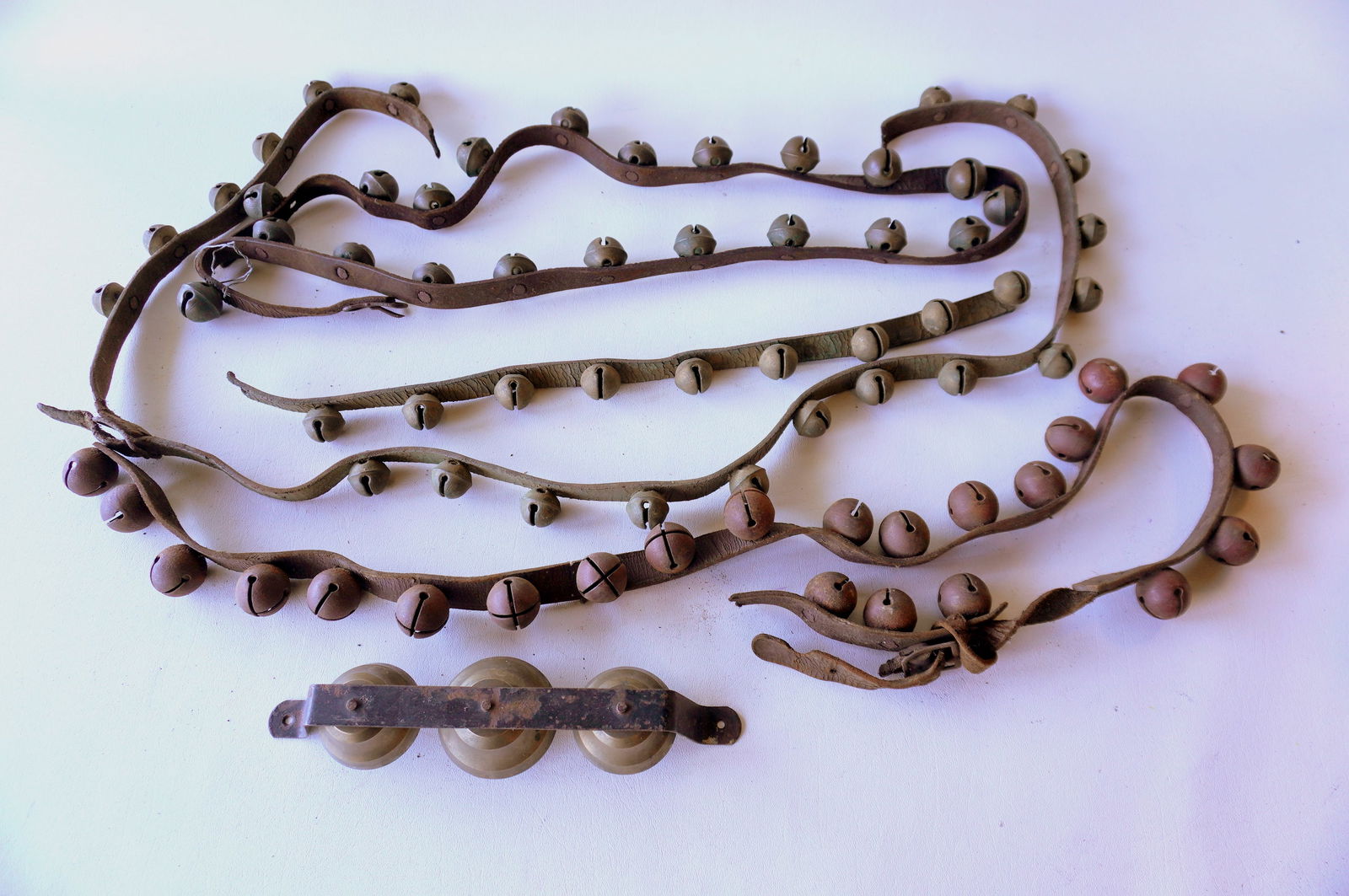 A grouping of incomplete sleigh bells with straps and 1 set of 3 carriage bells. See photos for more: A grouping of incomplete sleigh bells with straps and 1 set of 3 carriage bells. See photos for more details. Provenance: From the Marni Bakst and William Sadler collection of antiques, Verbank NY.