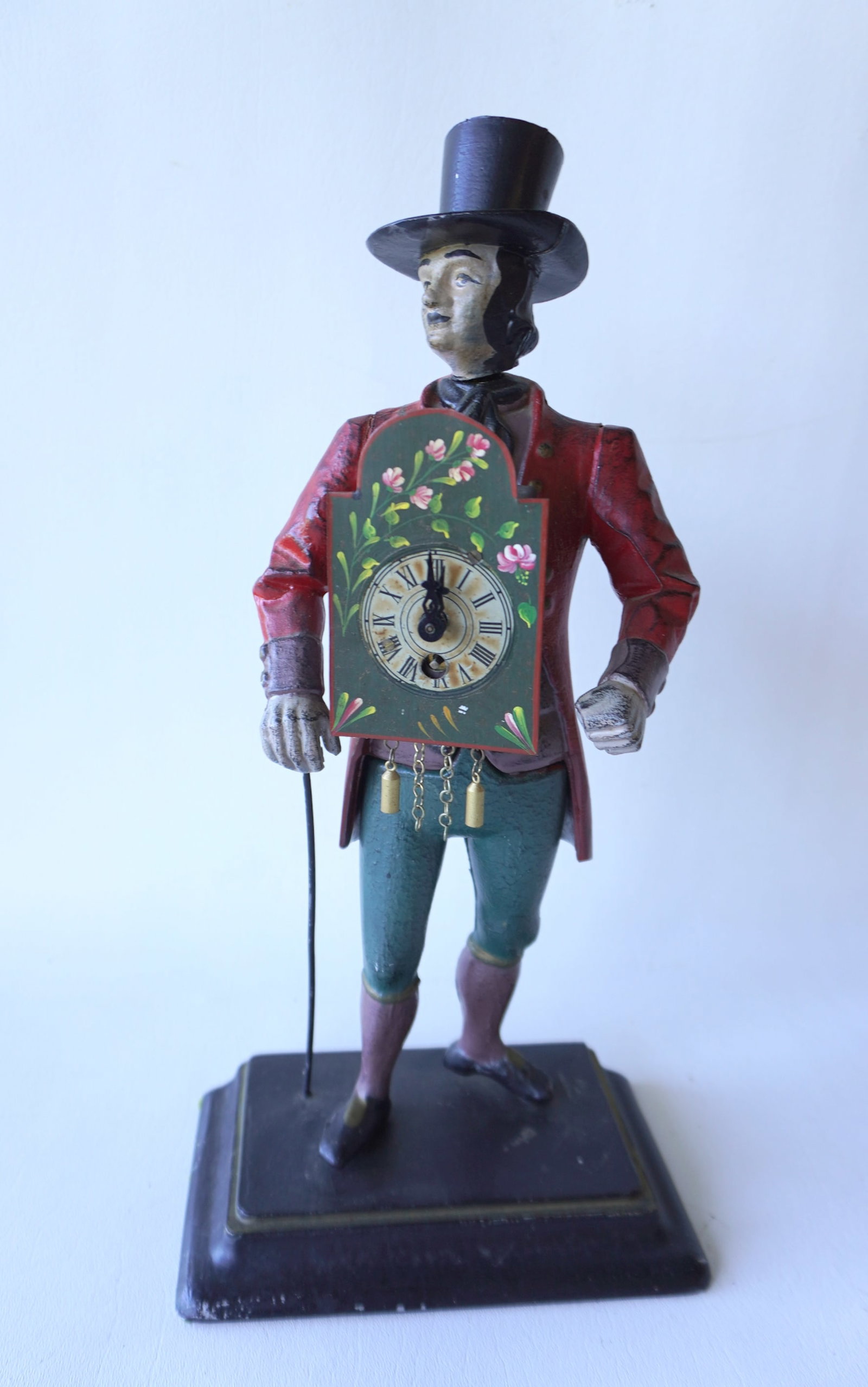 The Peddler clock, a hand painted cast metal novelty clock in the form of a clock peddler standing: The Peddler clock, a hand painted cast metal novelty clock in the form of a clock peddler standing on a stepped metal base, wearing top hat and carrying a walking stick, probably Dutch or German, earl