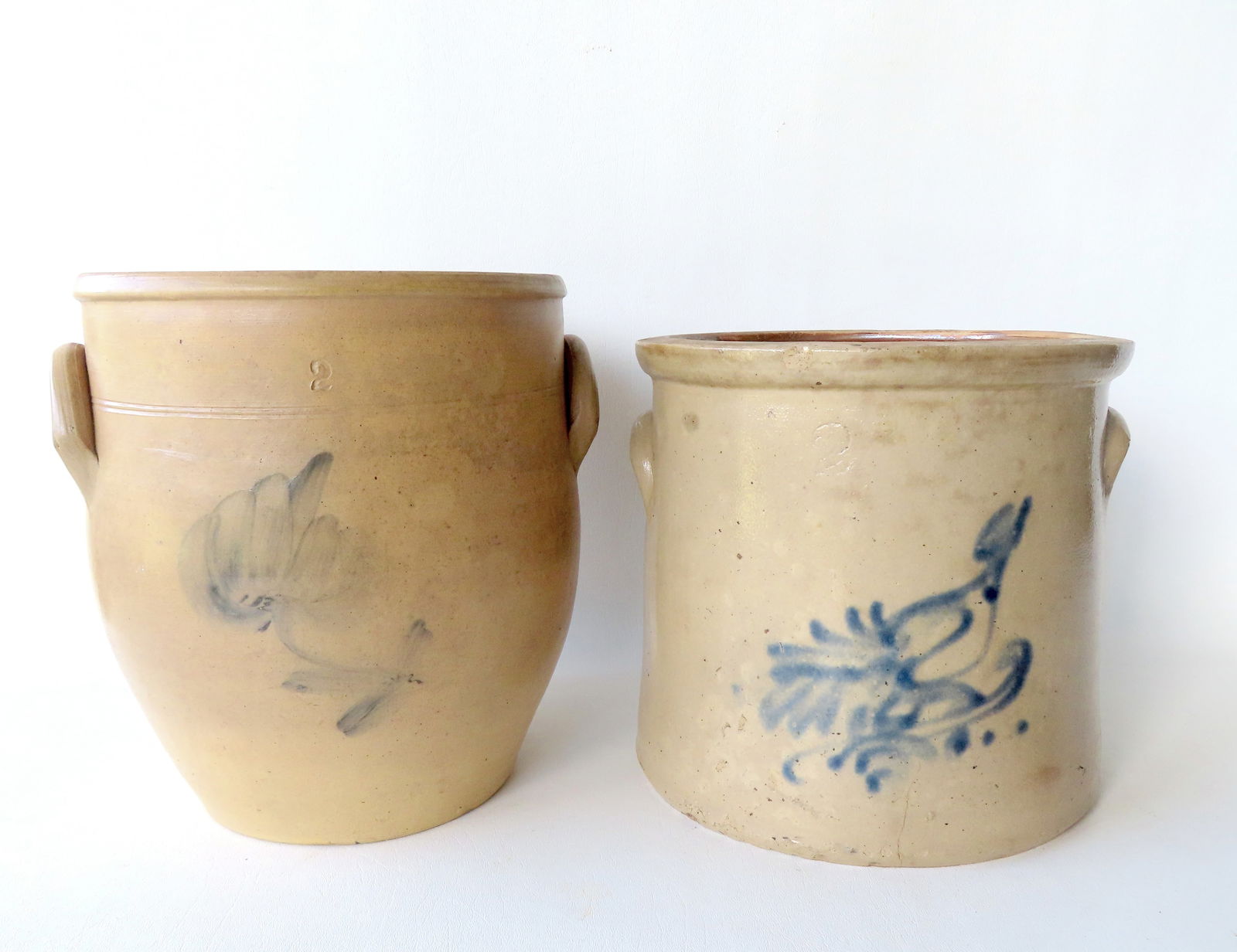 Two stoneware crocks, 2 gallon. The first decorated with a light cobalt blue flower - 10 3/4"H x 9: Two stoneware crocks, 2 gallon. The first decorated with a light cobalt blue flower - 10 3/4"H x 9 1/2" diameter - very good condition; the second decorated with a cobalt blue bird on branch - several