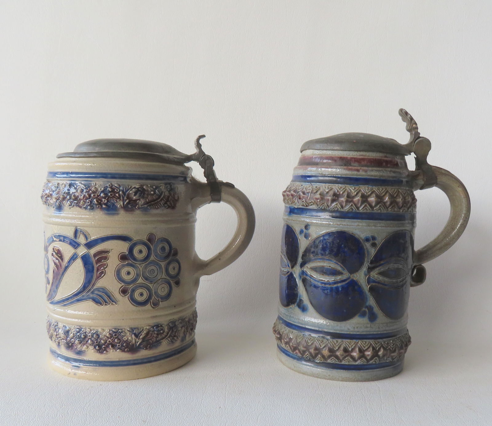 Two Westerwald stoneware cylindrical tankards, both with pewter lids and probably 18th century. The: Two Westerwald stoneware cylindrical tankards, both with pewter lids and probably 18th century. The first, with incised decorations washed in cobalt blue and purple manganese on all the decorations -