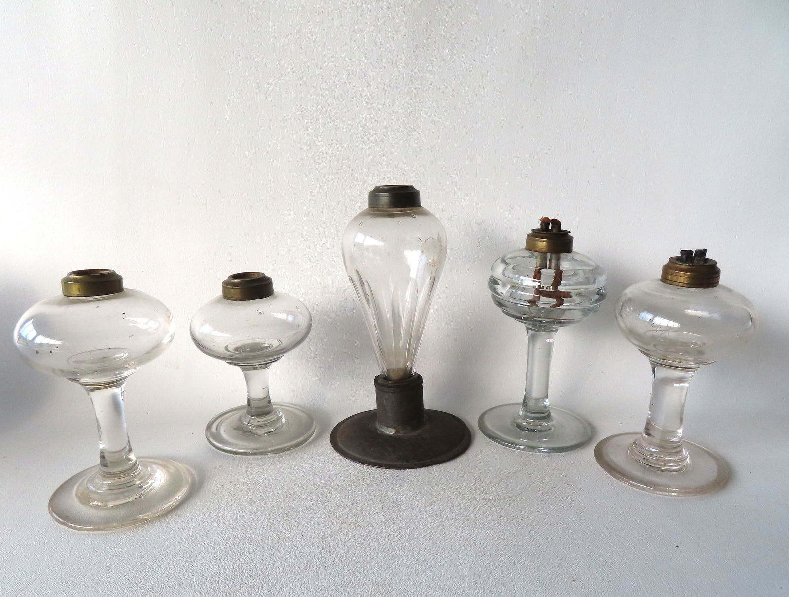 Five whale oil lamps, all hand blown, late 18th to early 19th century. The largest mounted on tin: Five whale oil lamps, all hand blown, late 18th to early 19th century. The largest mounted on tin base measures 7 3/4"H. All in good condition.