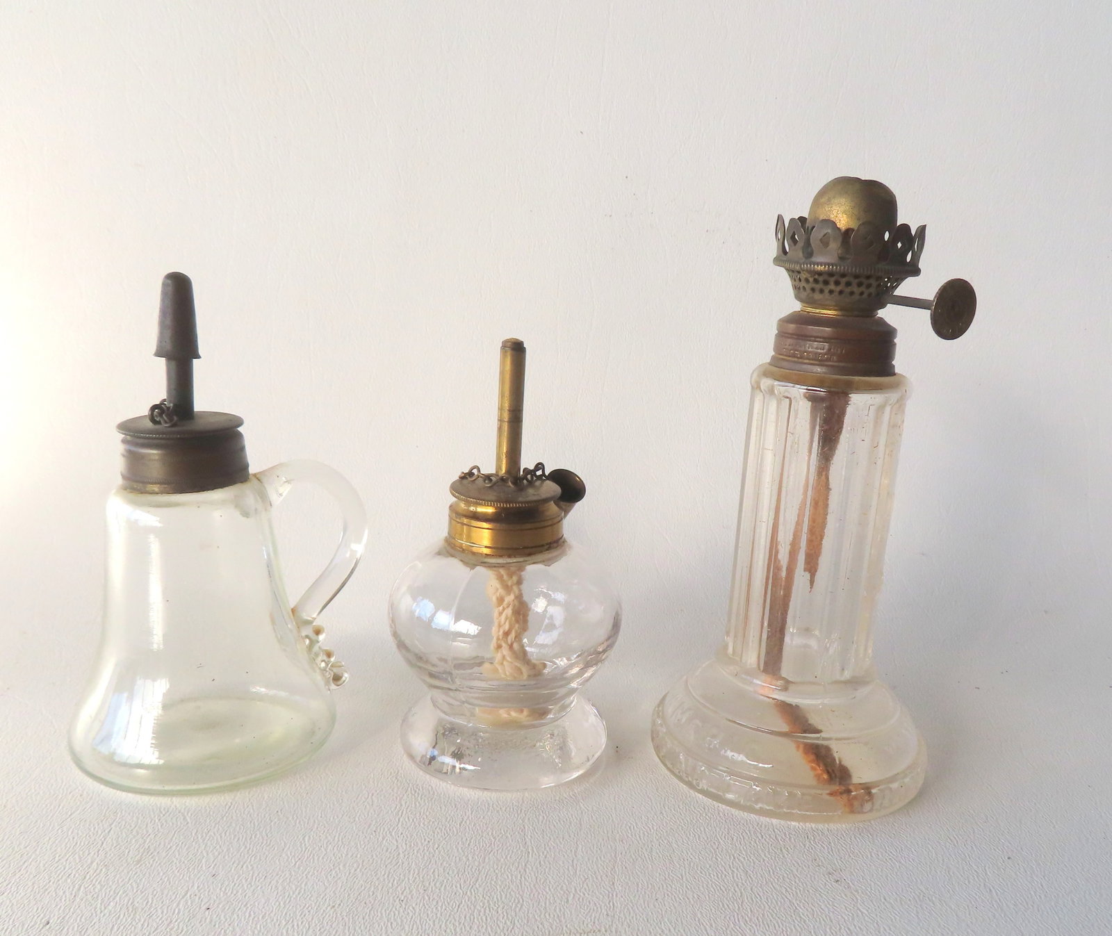 Three early miniature glass lamps including 2 spark lamps (one with applied handle), and 1 signed: Three early miniature glass lamps including 2 spark lamps (one with applied handle), and 1 signed "Pride of America / Time Indicating Lamp / Grand Vals Perfect" (missing chimney) - all in very good co