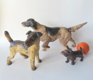 Two cast iron dog door stops and a cast iron dog paper weight, including: An Irish setter in