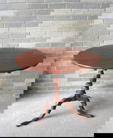 A cherry Queen Ann tilt top tea table with turned column leading to snake feet, late 18th century.