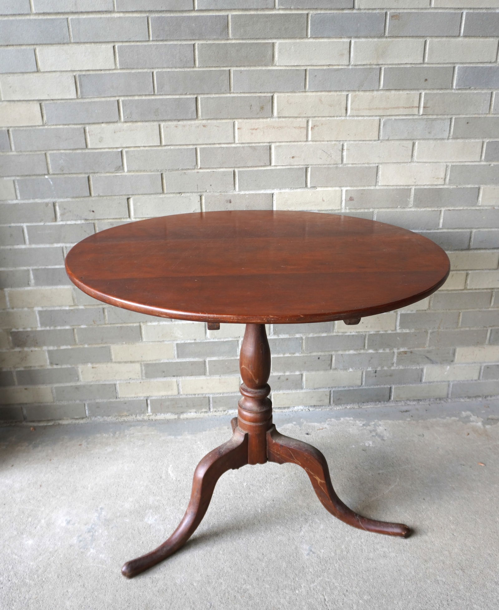 A cherry Queen Ann tilt top tea table with turned column leading to snake feet, late 18th century.: An American cherry Queen Ann tilt top tea table with turned column leading to snake feet, late 18th century. The top with scratch marks, but otherwise good condition. Measures 32 1/2" diameter x 28 1/