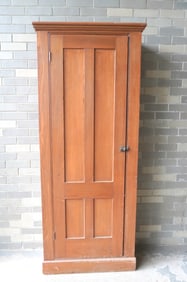 A poplar wood pantry cupboard with a single paneled door mounted on molded base, original natural