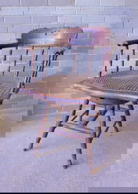 An unusual black walnut spindle back office chair with scrolled arms and cane seat, that is attached