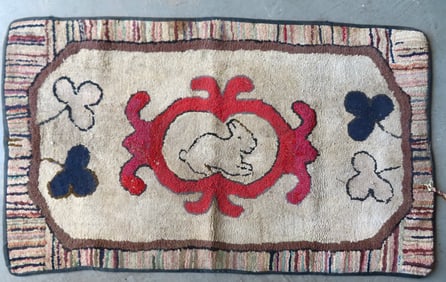 A primitive hooked rug having a central image of a rabbit within medallion - minor wool pulls and