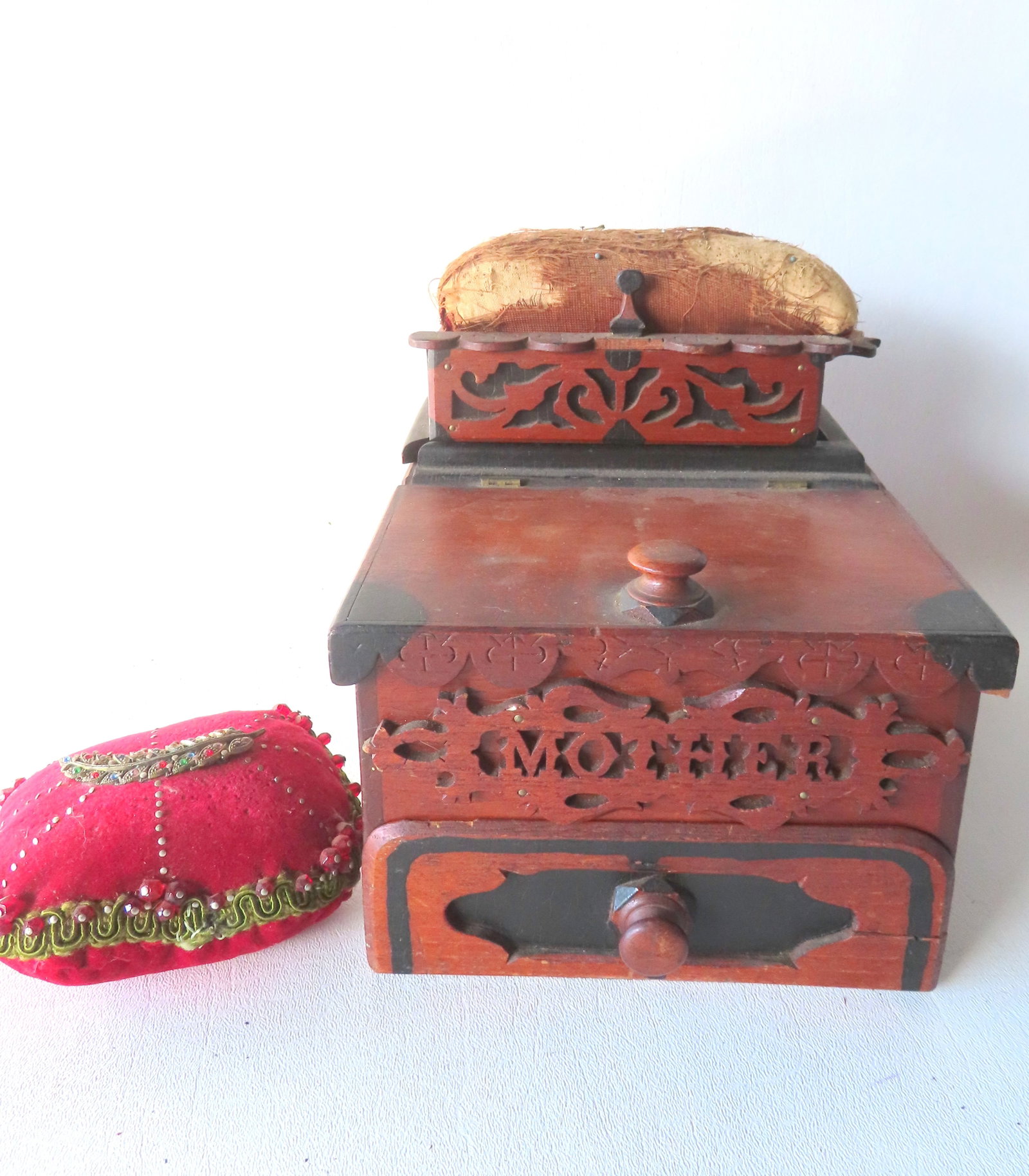 An usual folk art sewing box having a pin cushion top attached to sliding lid that covers a storage: An usual folk art sewing box having a pin cushion top attached to sliding lid that covers a storage area, over a lift top storage compartment with hand painted highlights in corners of lid, over a fro