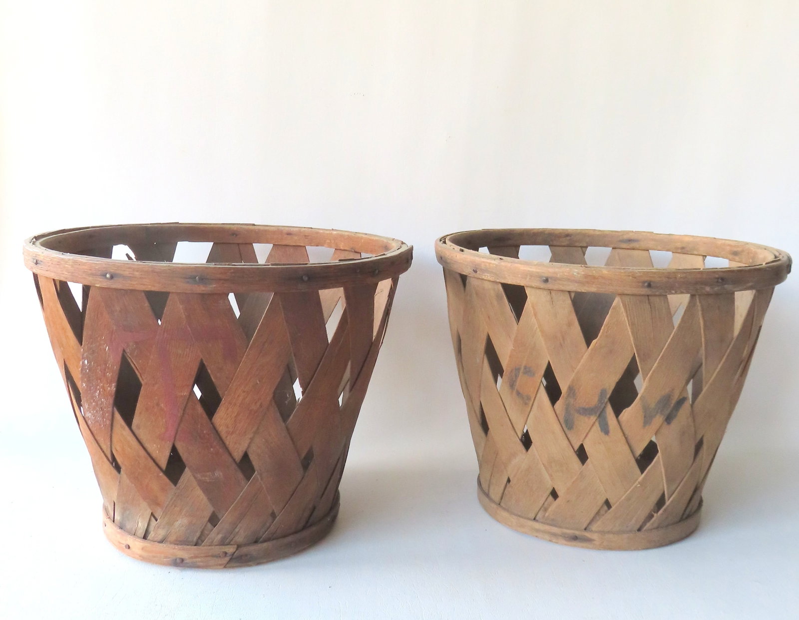 Two Shaker fruit baskets in woven diamond slatted pattern, one initialed "C H W" in black paint and: Two Shaker slatted wooden fruit baskets in woven diamond pattern, one initialed "C H W" in black paint on slat and one marked "T" in red paint on slat (this basket also initialed in red along edge of 