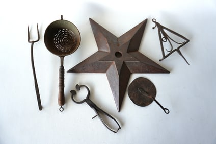 Grouping of early iron kitchen tools and an early cast iron building anchor ornament. Includes: A