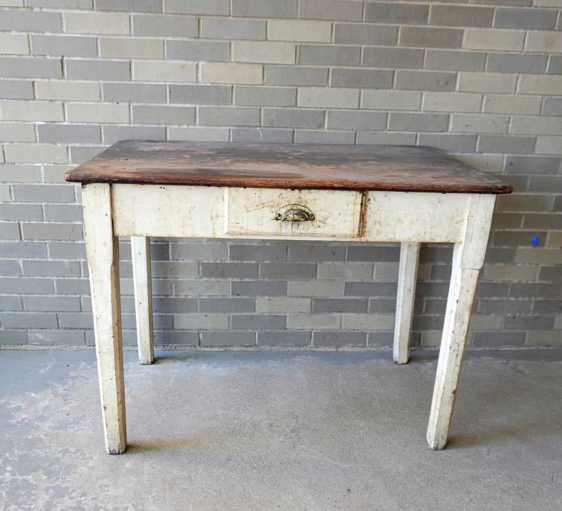 A primitive country work table in oak, with chamfered tapered legs and center drawer, partial white: A primitive country work table in oak, with chamfered tapered legs and center drawer, partial white paint on base, scrubbed top with use wear in old finish, late 19th century. Note the hand forged iro
